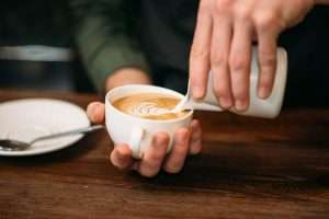 Milchschaum wird vorsichtig in eine mit Espresso gefüllte Tasse gefüllt