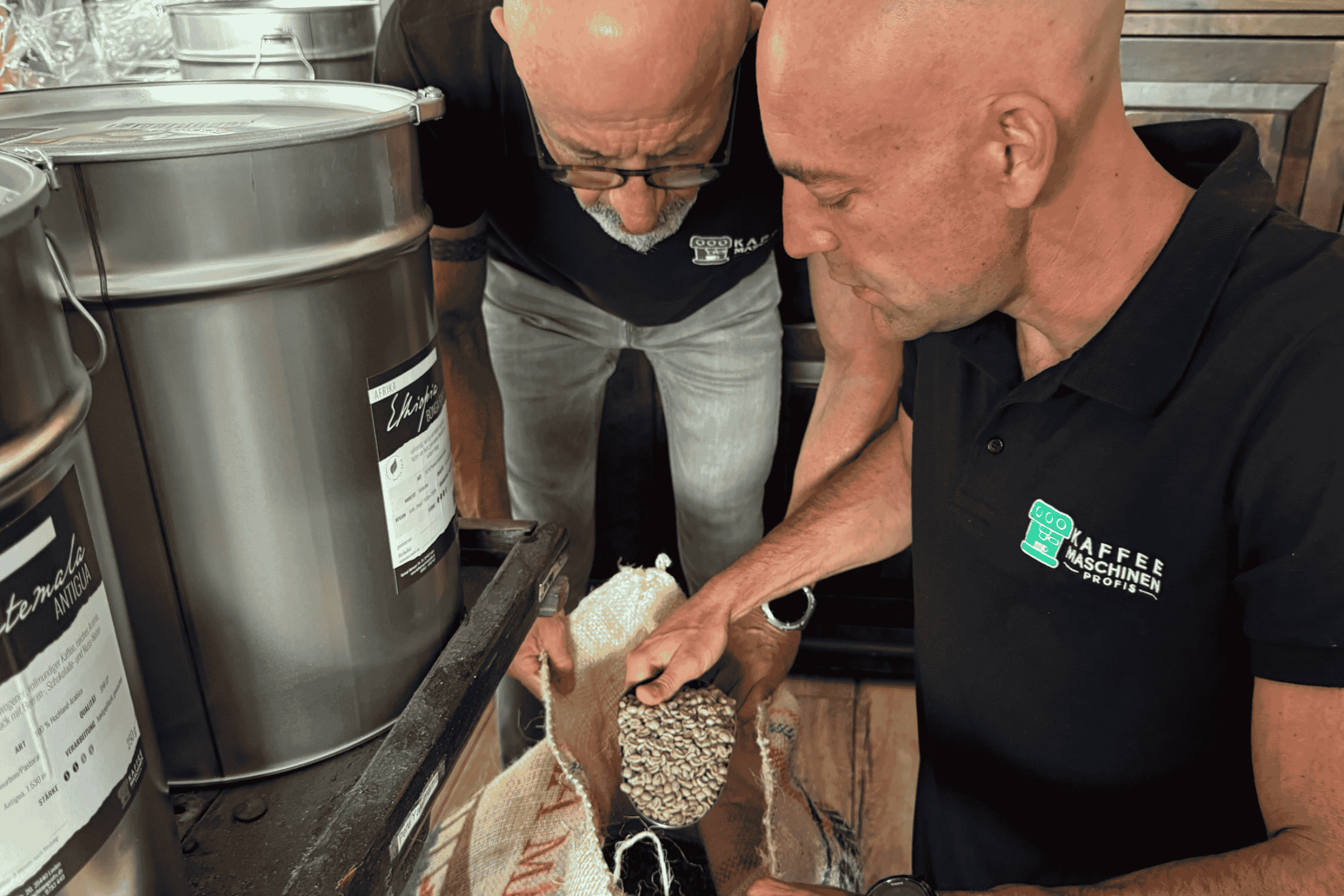 Wir über uns 2 In der Rösterei, Stefan und Thorsten beugen sich über Kaffeebohnen und bewerten deren Qualität
